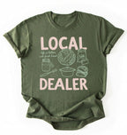Flat lay of a Moss_MilitaryGreen Funny local dealer bread shirt with baking tools and sourdough theme perfect gift for bakers and bread lovers on a white background 