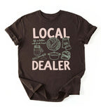 Flat lay of a dark chocolate Funny local dealer bread shirt with baking tools and sourdough theme perfect gift for bakers and bread lovers on a white background 