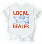Flat lay of a white Funny local dealer bread shirt with baking tools and sourdough theme perfect gift for bakers and bread lovers on a white background 