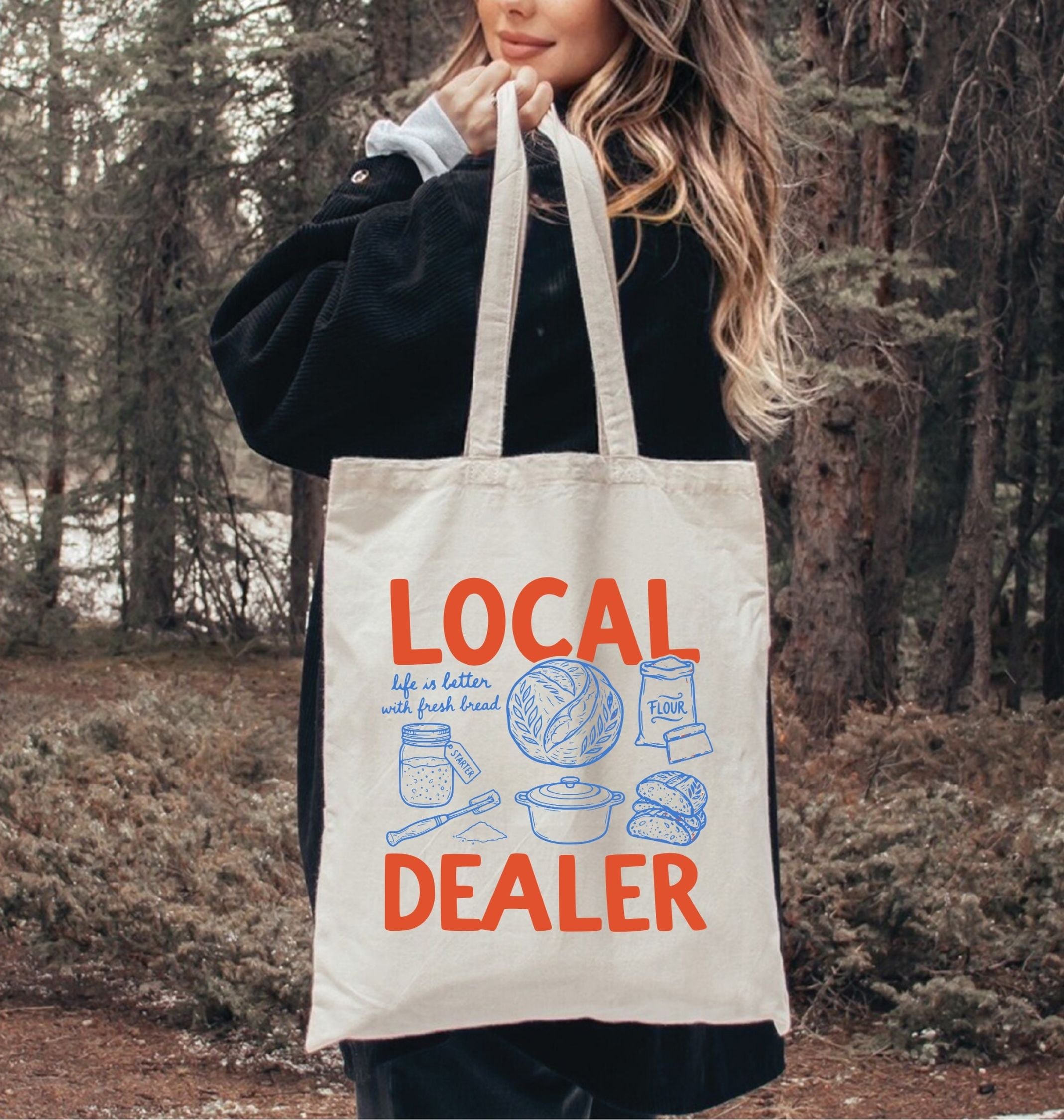 Person holding a tote bag with 'Local Dealer' text and graphics in a forest setting