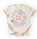 Flat lay of an ivory local dealer sourdough shirt with bread starter and baking illustrations funny baker gift white t-shirt on a white background