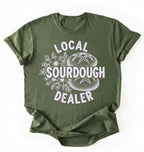 Flat lay of a green local sourdough dealer shirt brown funny baking t shirt bread lover gift bakery humor on a white background 