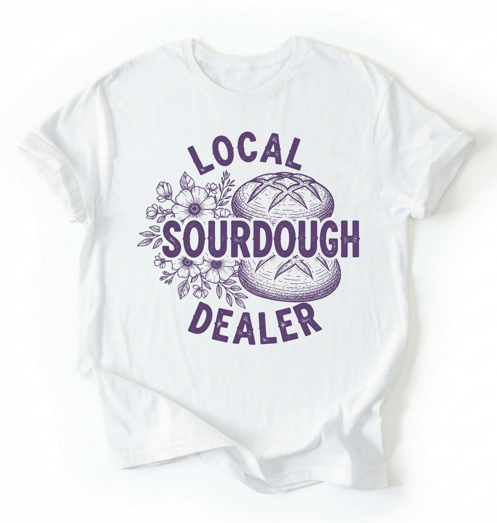 Flat lay of a white local sourdough dealer shirt brown funny baking t shirt bread lover gift bakery humor on a white background 