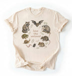 Flat lay of a ivory Nature inspired animal lover tee featuring raccoon, bat, frog, and opossum on a white background