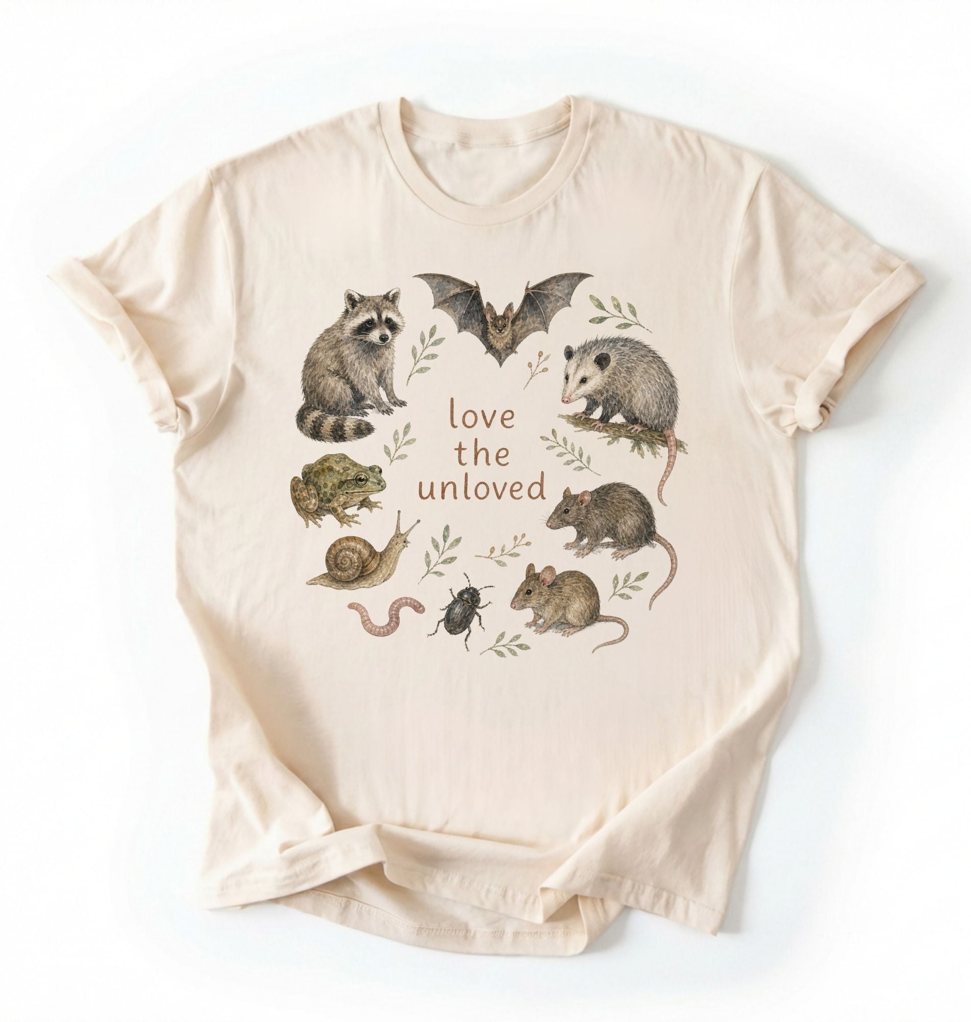 Flat lay of a ivory Nature inspired animal lover tee featuring raccoon, bat, frog, and opossum on a white background