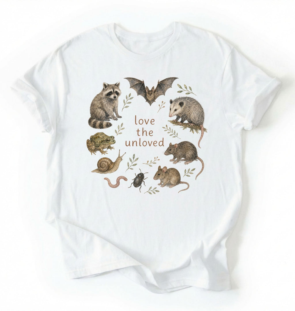 Flat lay of a white Nature inspired animal lover tee featuring raccoon, bat, frog, and opossum on a white background