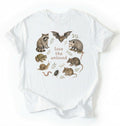 Flat lay of a white Nature inspired animal lover tee featuring raccoon, bat, frog, and opossum on a white background