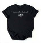 Flat lay of a black Funny Mama Makes The Dough shirt with bread graphic on brown tee on a white background