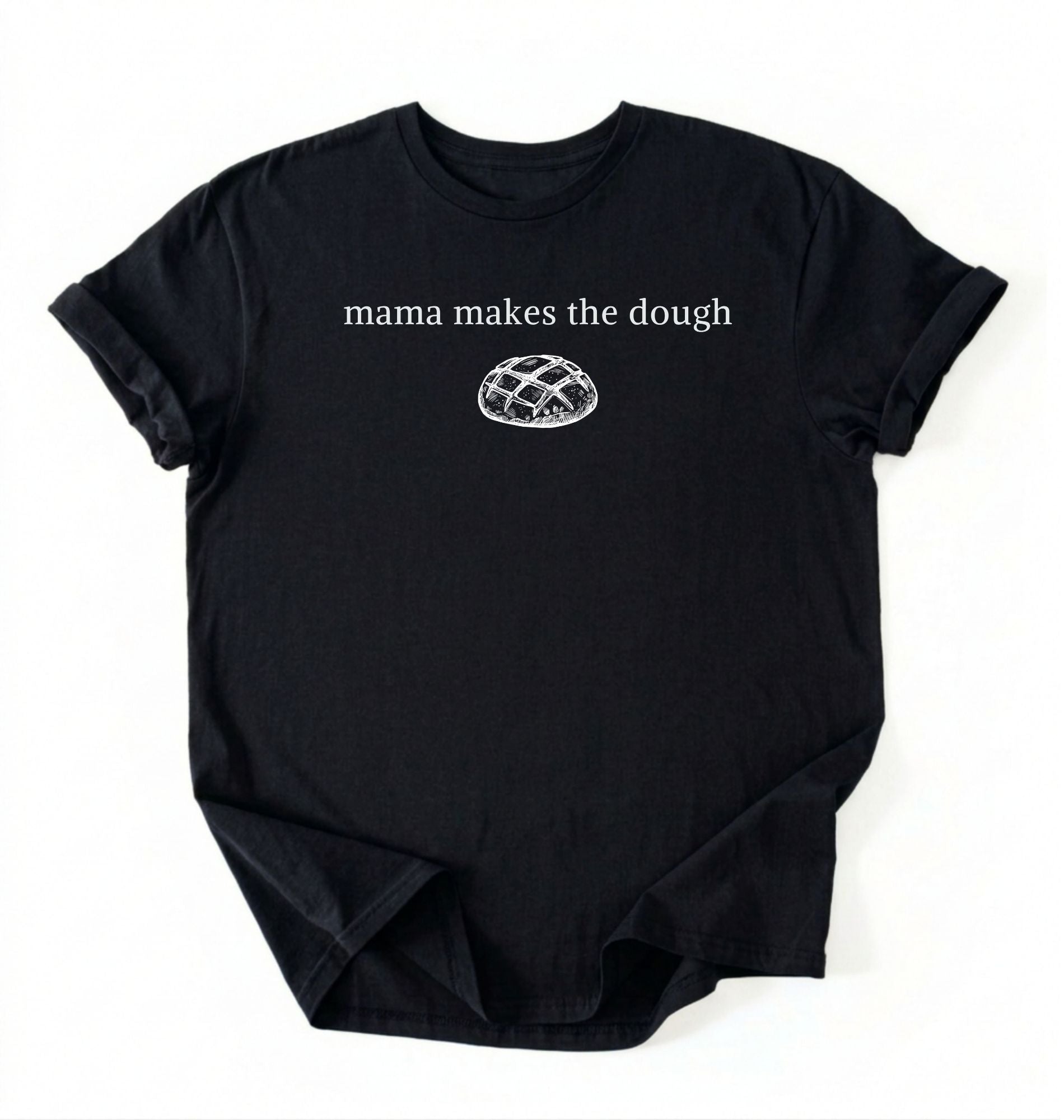 Flat lay of a black Funny Mama Makes The Dough shirt with bread graphic on brown tee on a white background