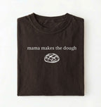 Flat lay of a darkchocolate Funny Mama Makes The Dough shirt with bread graphic on brown tee on a white background