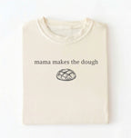 Flat lay of a ivory Funny Mama Makes The Dough shirt with bread graphic on brown tee on a white background