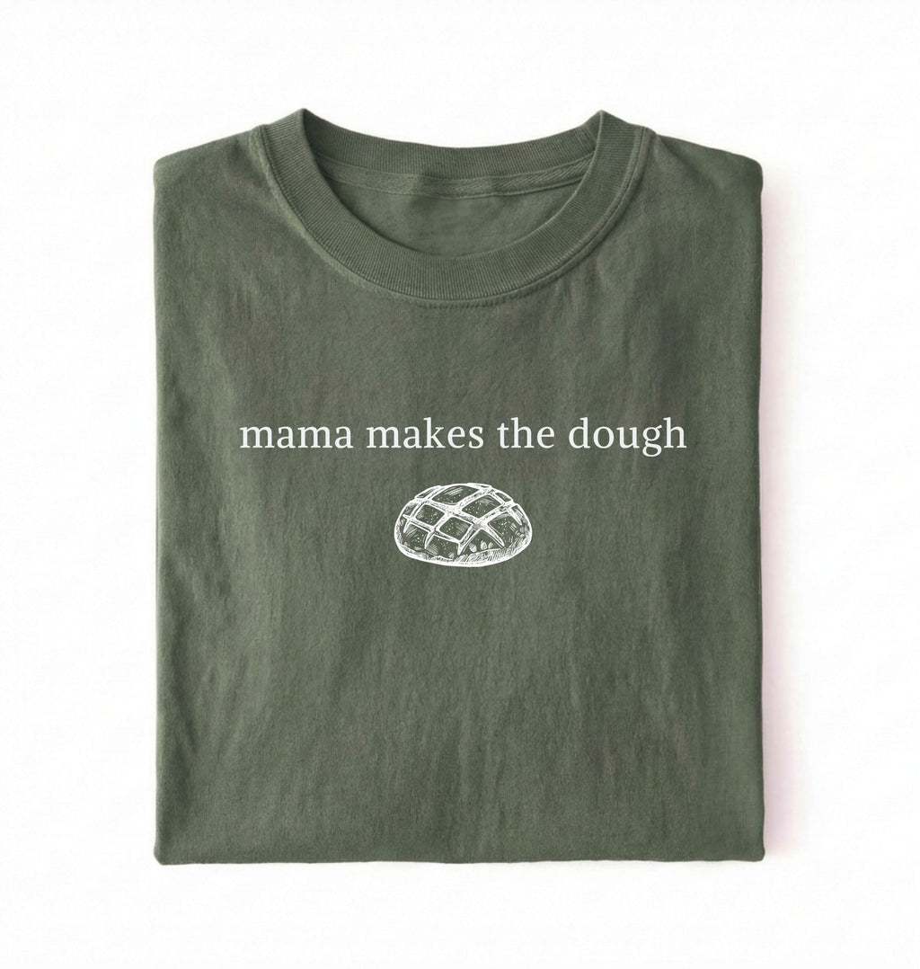 Flat lay of a military green Funny Mama Makes The Dough shirt with bread graphic on brown tee on a white background