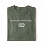 Flat lay of a military green Funny Mama Makes The Dough shirt with bread graphic on brown tee on a white background