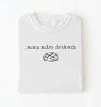 Flat lay of a white Funny Mama Makes The Dough shirt with bread graphic on brown tee on a white background