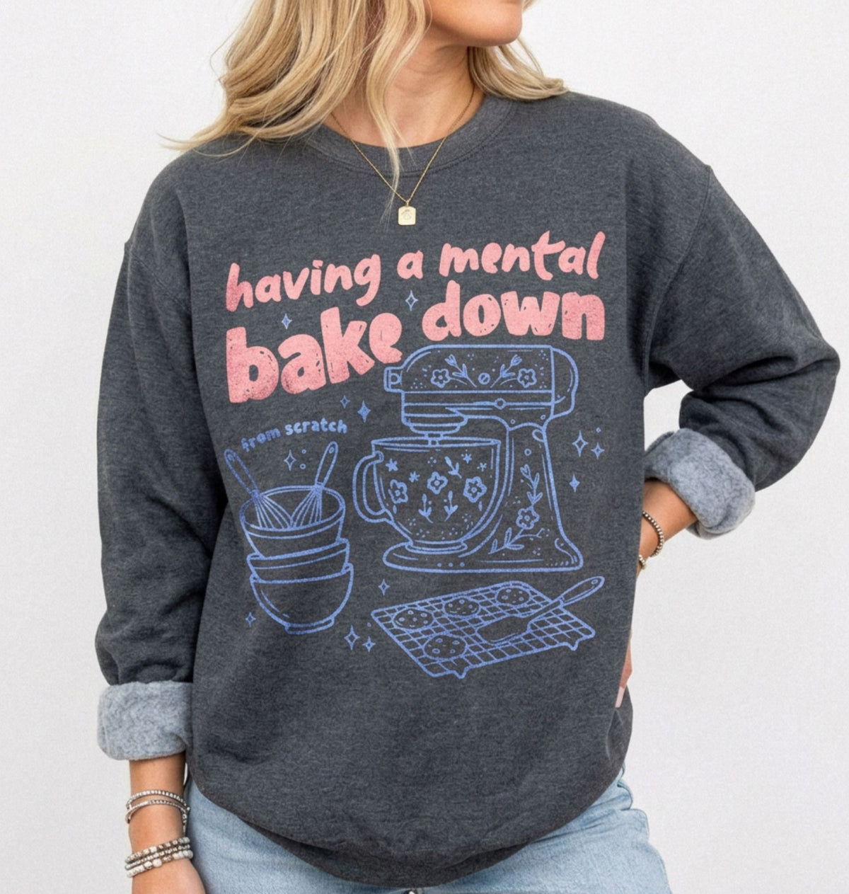 woman standing wearing a dark grey heather sweatshirt with a graphic that says "having a mental bake down"