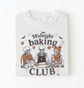 A white short-sleeve t-shirt with a Halloween-themed graphic print that reads 'Midnight baking CLUB' featuring three cartoon skeletons baking together.