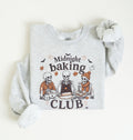 A light heather gray long-sleeve sweatshirt with a cozy rolled cuff, laid flat on a warm off-white background. The front features a graphic of three cartoon skeletons baking together with the text 'Midnight baking CLUB' and small autumn-themed illustrations.