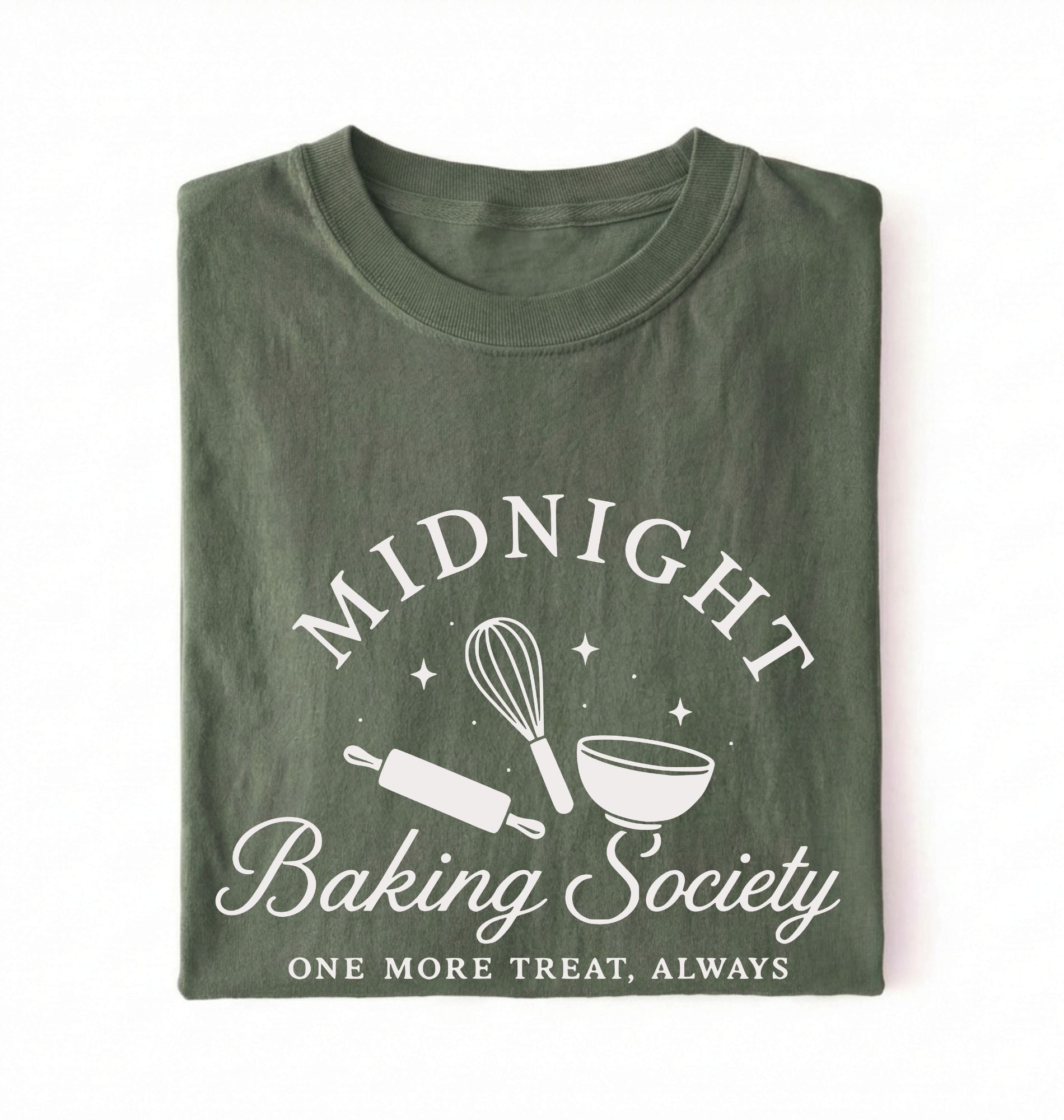 A folded dark olive green t-shirt with a white graphic print that reads 'MIDNIGHT Baking Society' and 'ONE MORE TREAT, ALWAYS' with illustrations of a whisk, rolling pin, and bowl on a white background