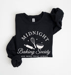 A black long-sleeve sweatshirt with rolled cuffs, featuring a white graphic print that reads 'MIDNIGHT Baking Society' and 'ONE MORE TREAT, ALWAYS' with baking tools like a whisk, rolling pin, and bowl. Photographed flat on a white background.