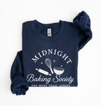 Flat lay of a navy blue Gildan sweatshirt featuring a rolling pin, whisk and mixing bowl with the phrase Midnight Baking Society