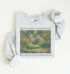 Flat lay of a light gray crewneck sweatshirt on a white background, featuring an impressionist floral garden artwork and black text reading “Money doesn’t buy happiness, but it buys plants, so close enough.