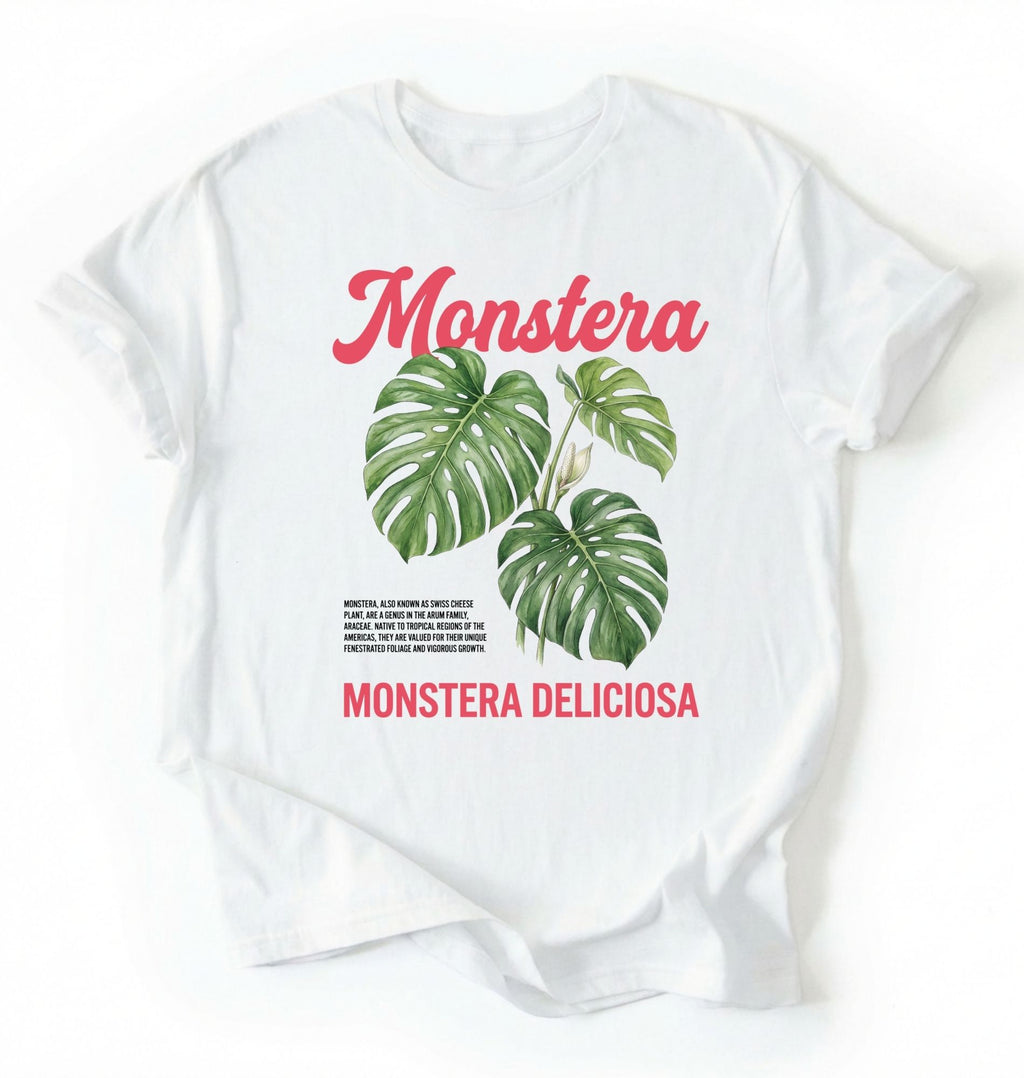 Flat lay of a white t-shirt featuring a botanical illustration of Monstera leaves with text reading “Monstera Deliciosa.” plant shirt with tropical leaf illustration perfect gift for plant lovers and houseplant enthusiasts on a white background