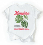 Flat lay of a white t-shirt featuring a botanical illustration of Monstera leaves with text reading “Monstera Deliciosa.” plant shirt with tropical leaf illustration perfect gift for plant lovers and houseplant enthusiasts on a white background