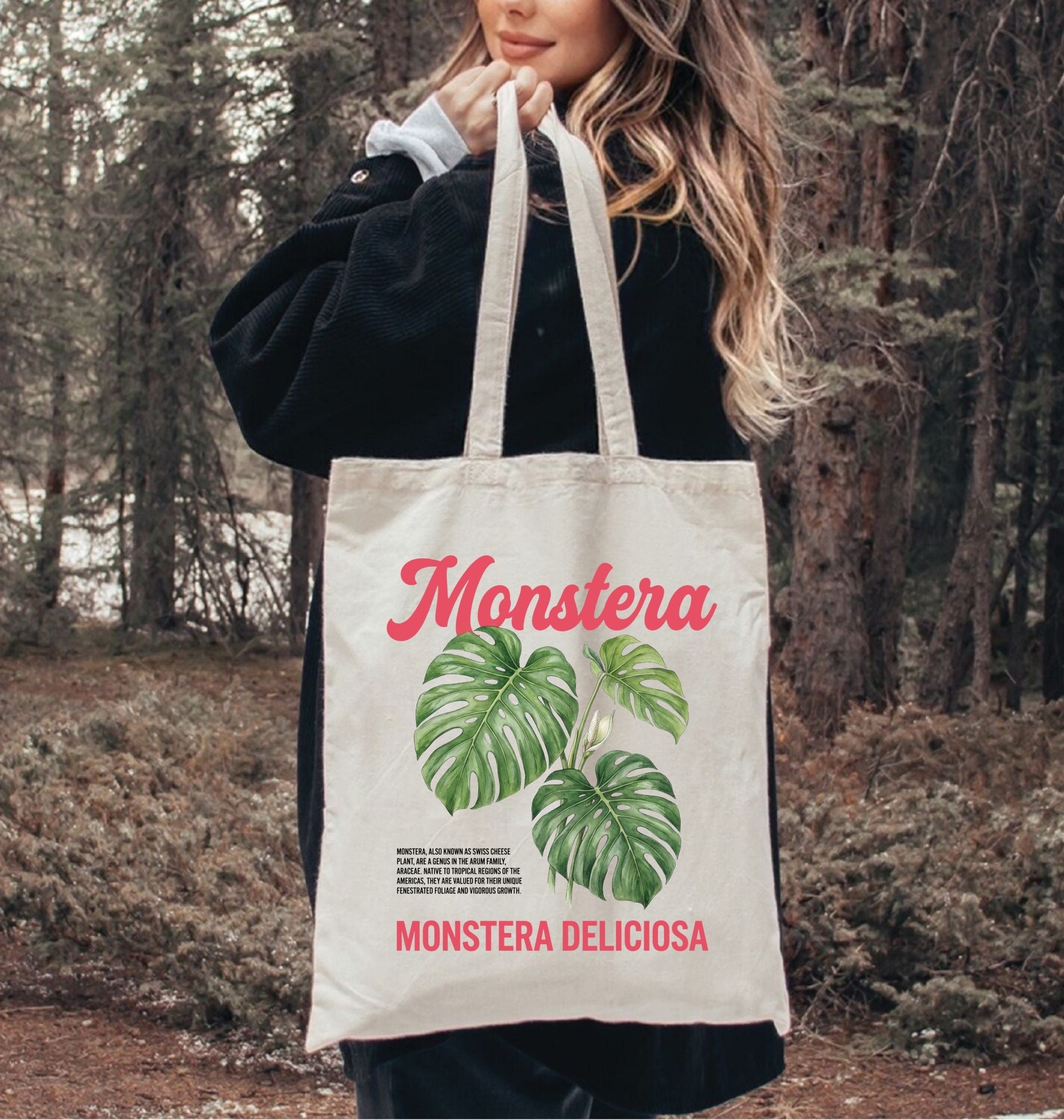 Person holding a tote bag with 'Monstera' design in a forest setting