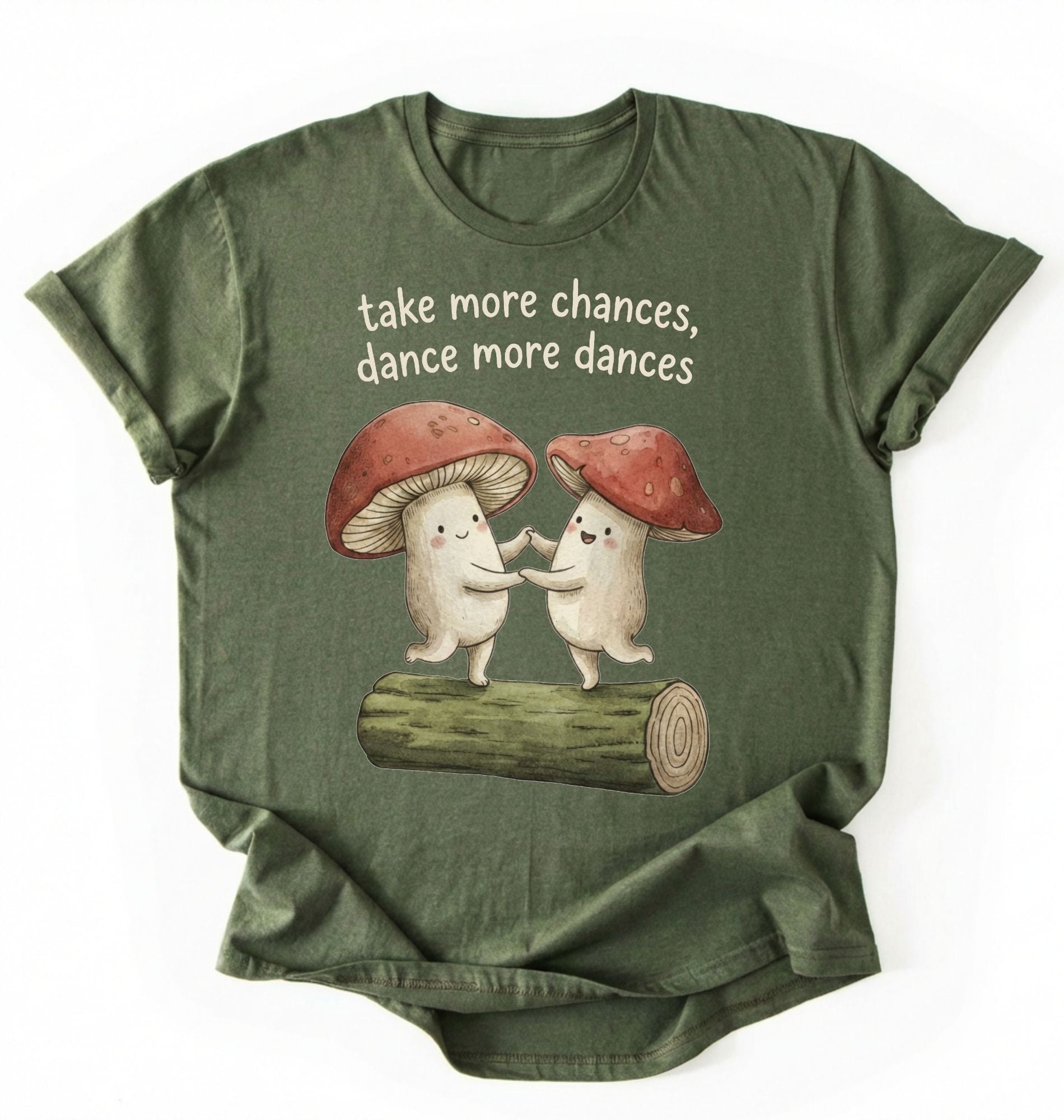 Flat lay of a Moss_Military_Green t-shirt with two dancing mushrooms and the phrase take more chances dance more dances, whimsical cottagecore gift tee on a white background 