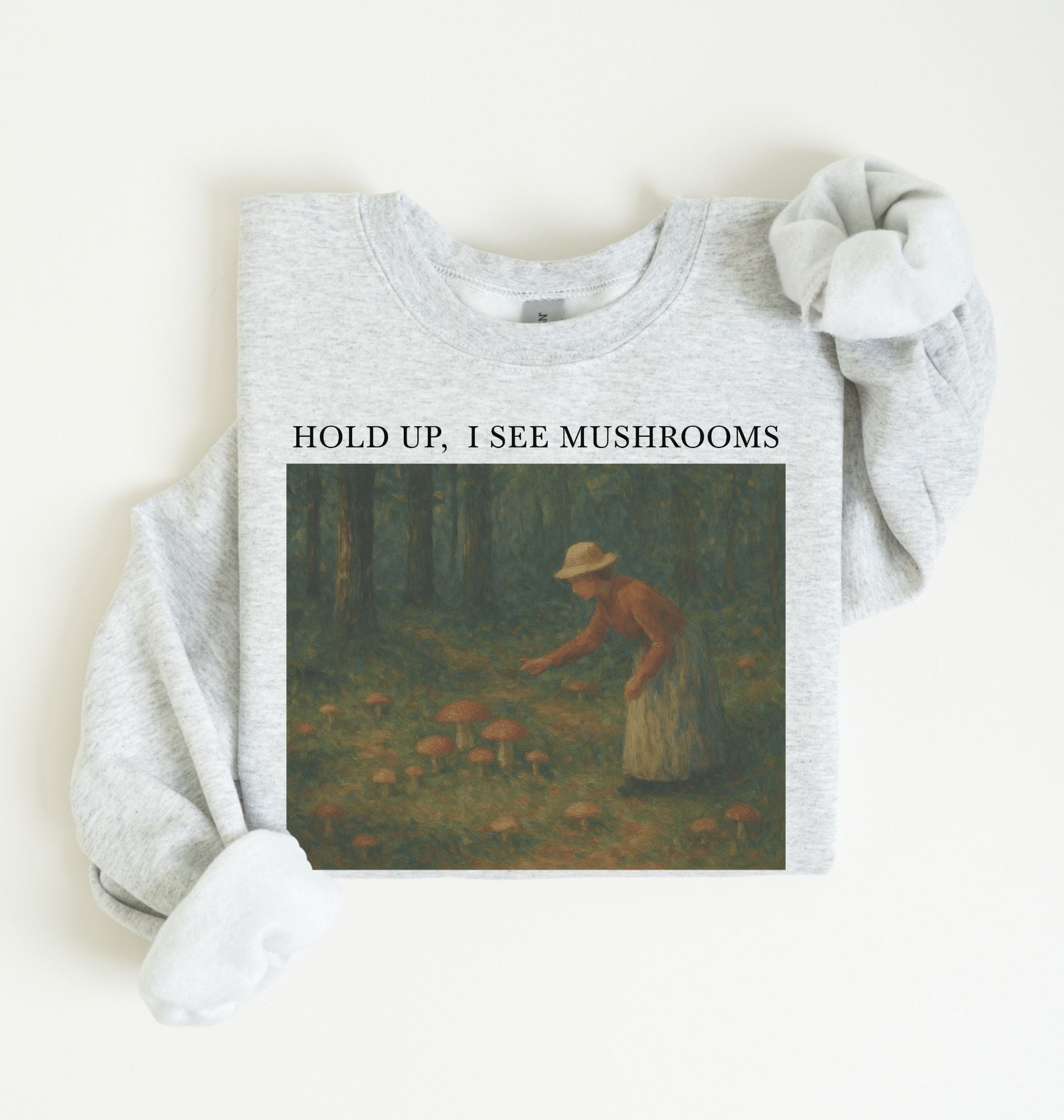 Flat lay of an ash Cottagecore mushroom sweatshirt Hold Up I See Mushrooms design beige crewneck for nature lovers on a white background