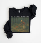 Flat lay of an black Cottagecore mushroom sweatshirt Hold Up I See Mushrooms design beige crewneck for nature lovers on a white background