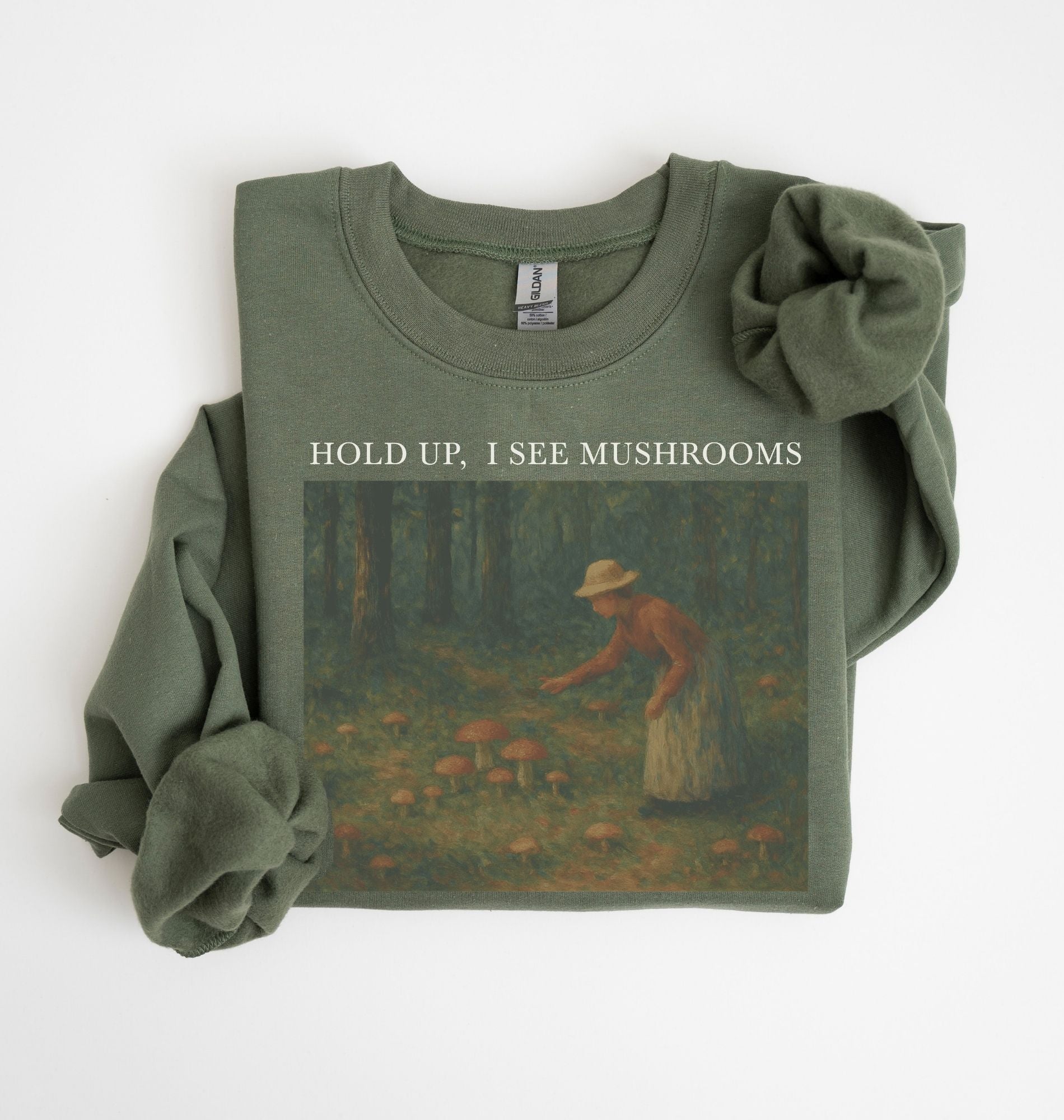 Flat lay of an military green Cottagecore mushroom sweatshirt Hold Up I See Mushrooms design beige crewneck for nature lovers on a white background