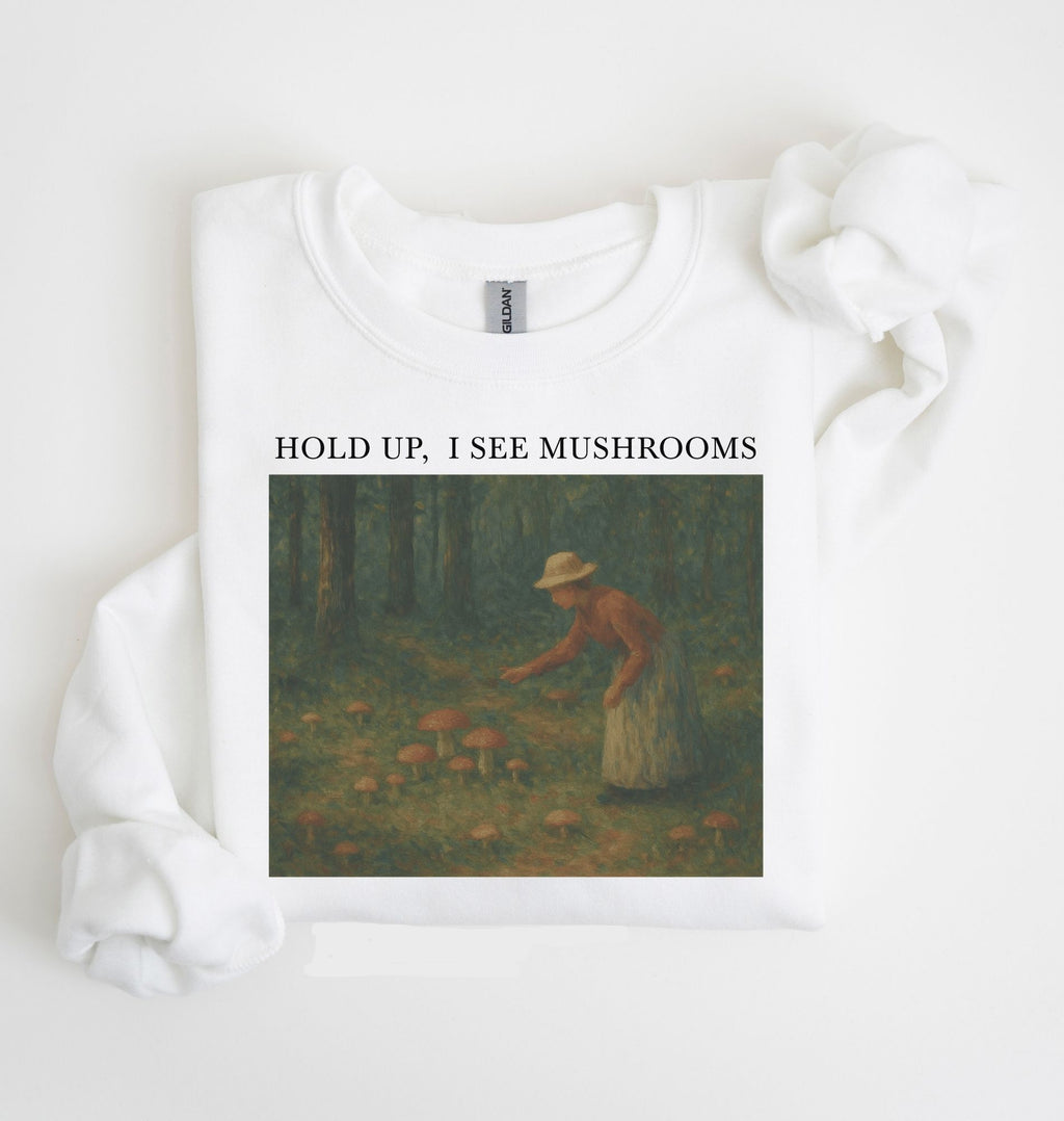 Flat lay of an white Cottagecore mushroom sweatshirt Hold Up I See Mushrooms design beige crewneck for nature lovers on a white background