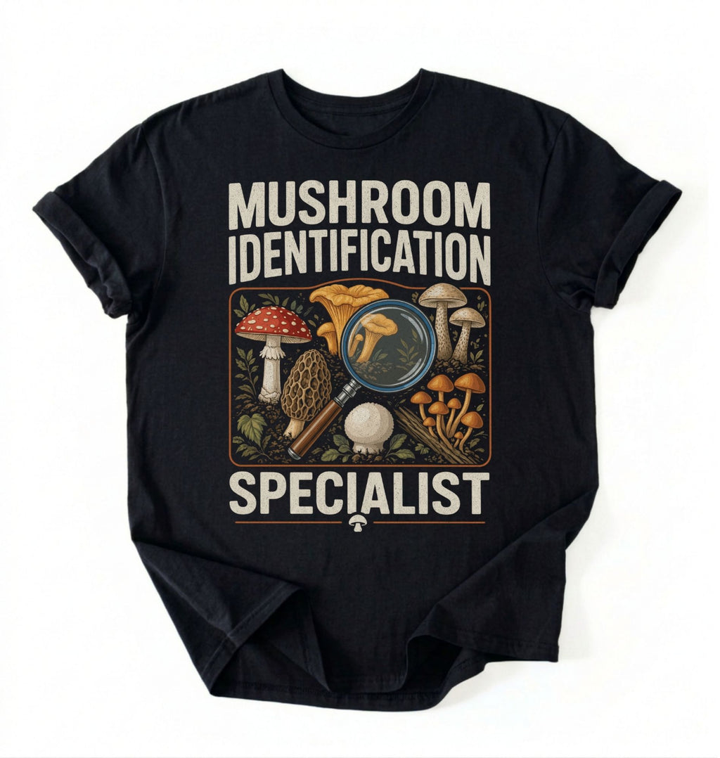 Flat lay of a black mushroom identification specialist shirt black funny foraging t shirt fungi lover gift nature hiking design on a white background 