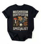 Flat lay of a black mushroom identification specialist shirt black funny foraging t shirt fungi lover gift nature hiking design on a white background 