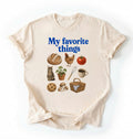 Flat lay of a cream my favorite things shirt with bread chicken coffee plants and cottagecore homestead illustrations on a white background