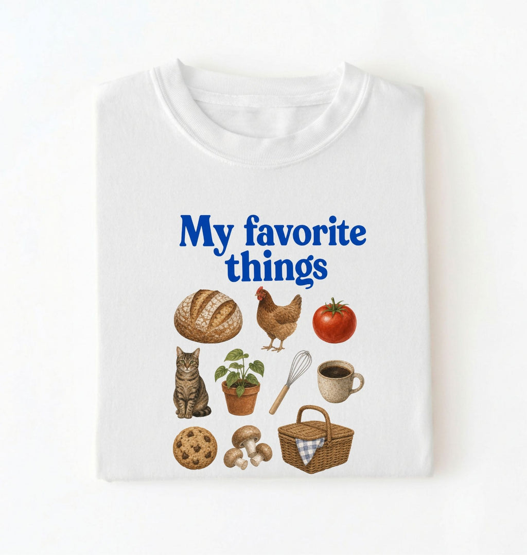 Flat lay of a white my favorite things shirt with bread chicken coffee plants and cottagecore homestead illustrations on a white background