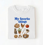 Flat lay of a white my favorite things shirt with bread chicken coffee plants and cottagecore homestead illustrations on a white background