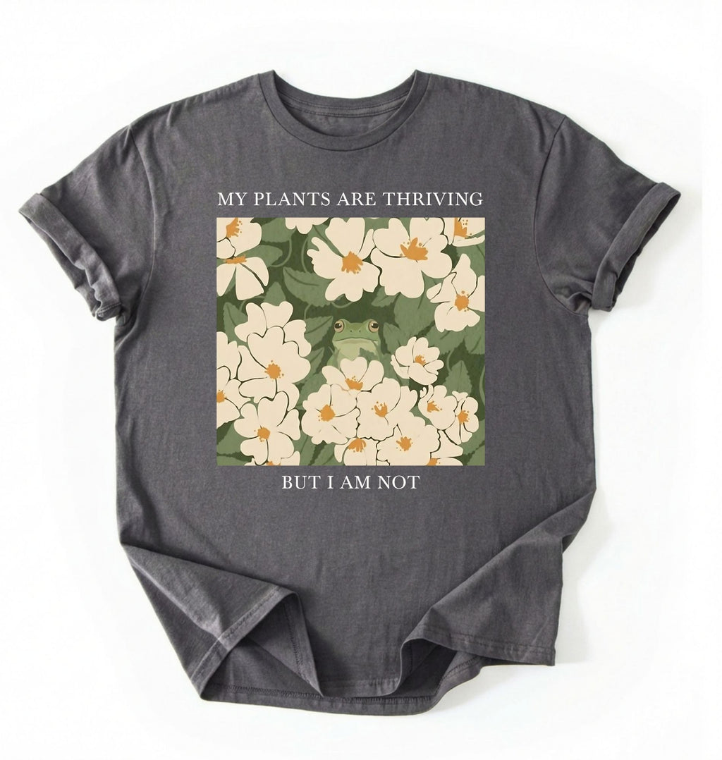Flat lay of a Charcoal Gardener t-shirt with floral design and text my plants are thriving but i am not plant lover gift on a white background 