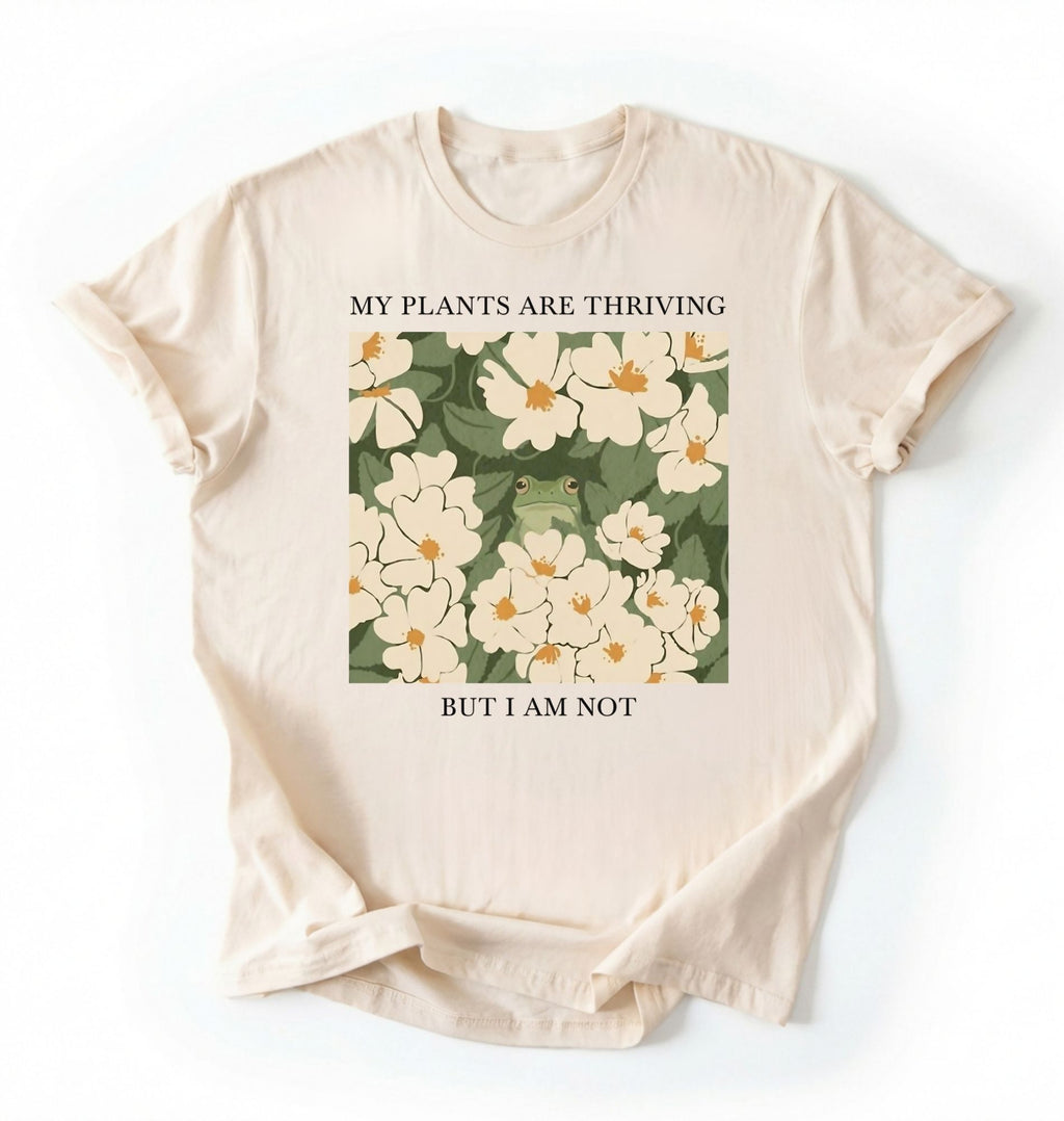 Flat lay of an ivory Gardener t-shirt with floral design and text my plants are thriving but i am not plant lover gift on a white background 