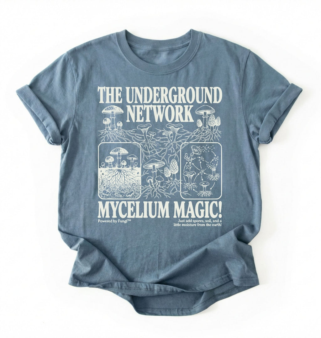 Flat lay of a stoneblue t-shirt featuring Mycelium network mushroom and root network illustrations with text reading “The Underground Network Mycelium Magic” with forest fungi design perfect gift for mushroom lovers nature fans and cottagecore style on a white background 