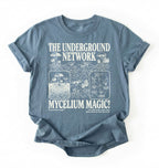 Flat lay of a stoneblue t-shirt featuring Mycelium network mushroom and root network illustrations with text reading “The Underground Network Mycelium Magic” with forest fungi design perfect gift for mushroom lovers nature fans and cottagecore style on a white background 