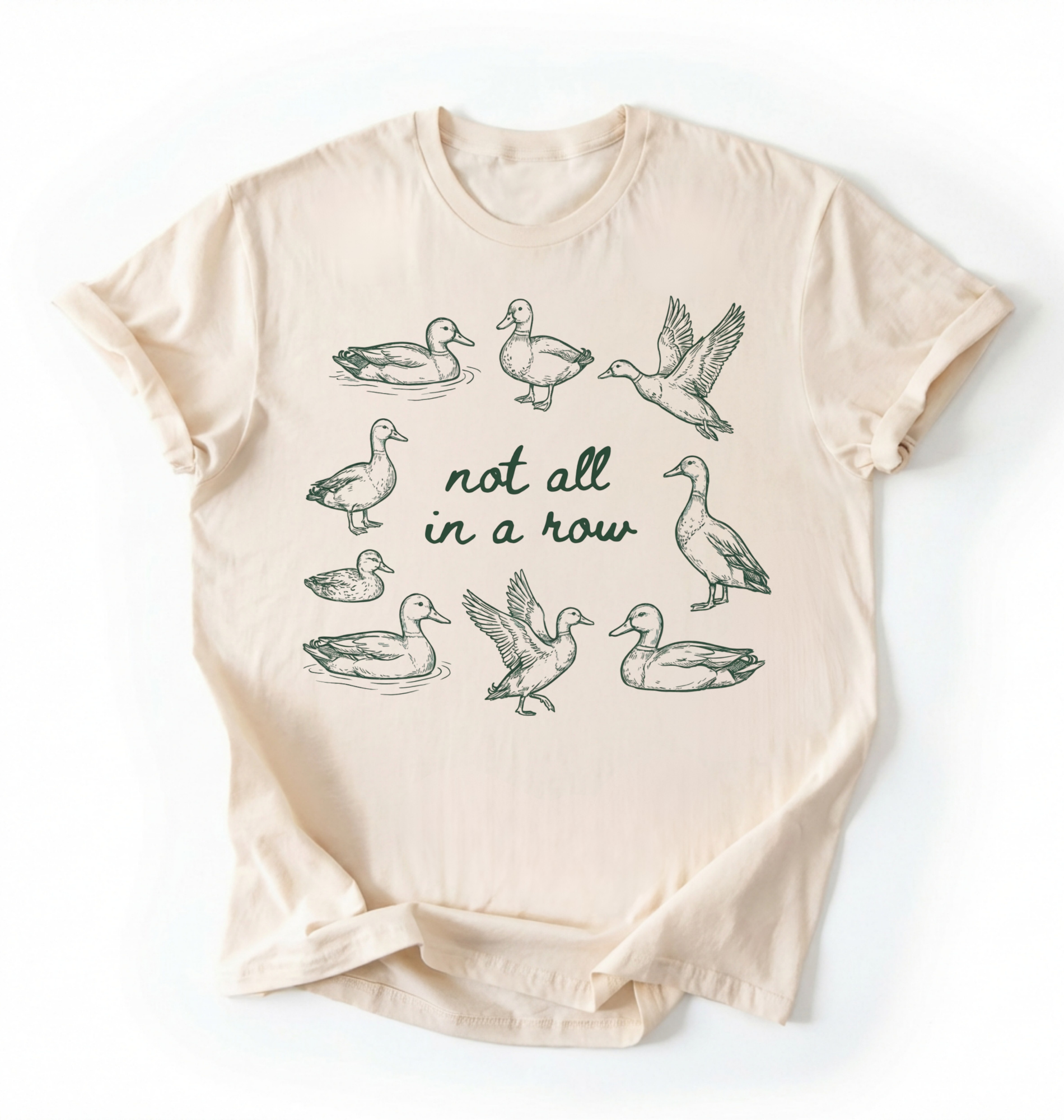 Flat lay of an Ivory duck graphic t-shirt with hand drawn ducks and not all in a row text, funny animal shirt gift on a white background 