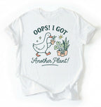 Flat lay white t-shirt with a graphic of a duck holding a plant and text 'Oops! I got another plant!' on a white background