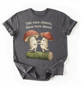 Flat lay of a Pepper charcoal t-shirt with two dancing mushrooms and the phrase take more chances dance more dances, whimsical cottagecore gift tee on a white background 