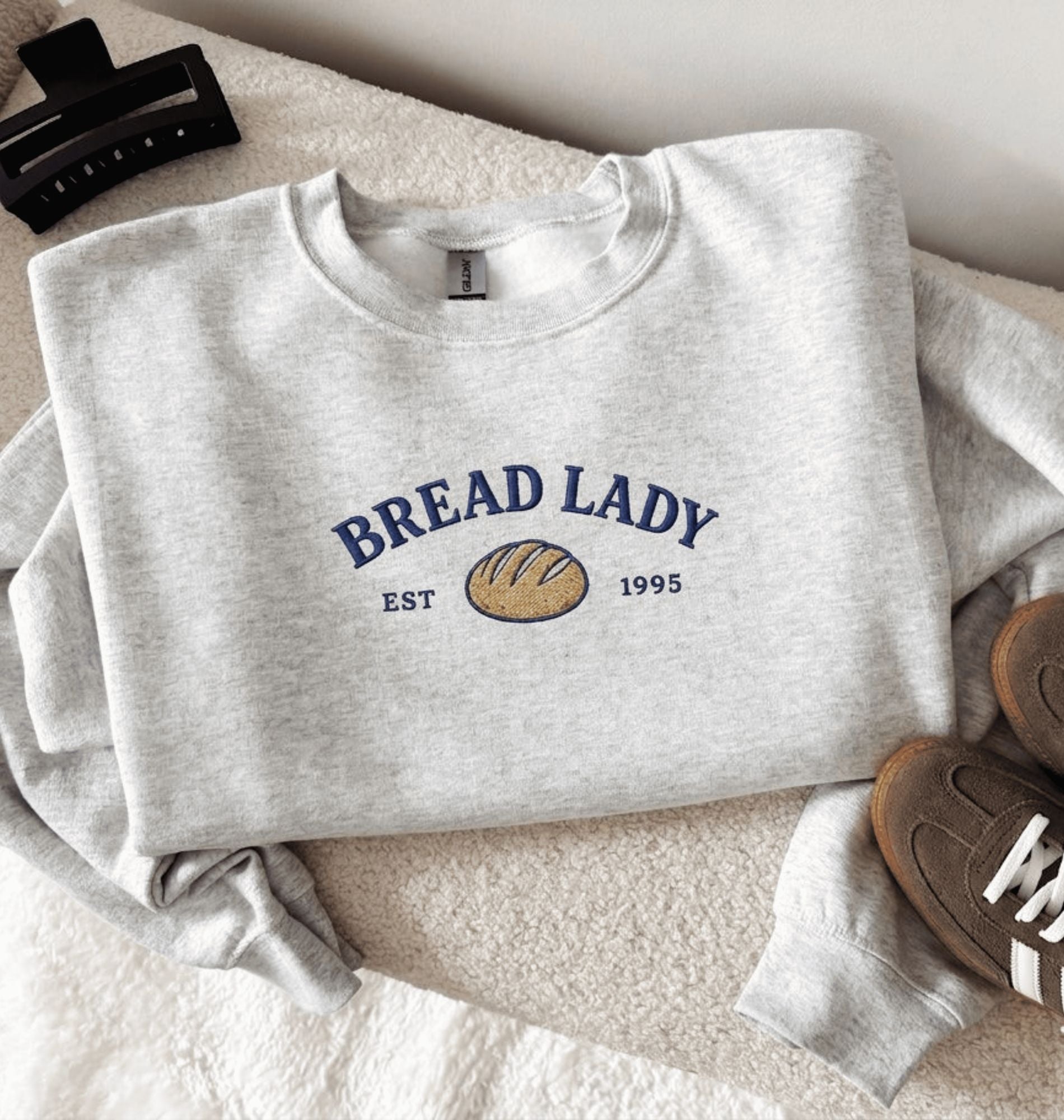 Gray sweatshirt with 'Bread Lady' design on a textured surface