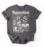 Flat lay of a Charcoal t-shirt featuring a botanical diagram with text reading “Photosynthesis Power Up.” for plant lovers and science fans perfect gardening gift for biology teachers and nature enthusiasts on a white background  