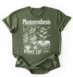 Flat lay of a military green t-shirt featuring a botanical diagram with text reading “Photosynthesis Power Up.” for plant lovers and science fans perfect gardening gift for biology teachers and nature enthusiasts on a white background 