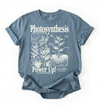 Flat lay of a stoneblue t-shirt featuring a botanical diagram with text reading “Photosynthesis Power Up.” for plant lovers and science fans perfect gardening gift for biology teachers and nature enthusiasts on a white background  