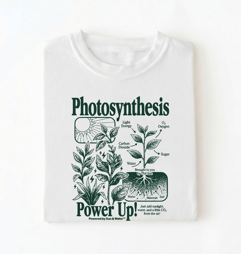 Flat lay of a white t-shirt featuring a botanical diagram with text reading “Photosynthesis Power Up.” for plant lovers and science fans perfect gardening gift for biology teachers and nature enthusiasts on a white background  
